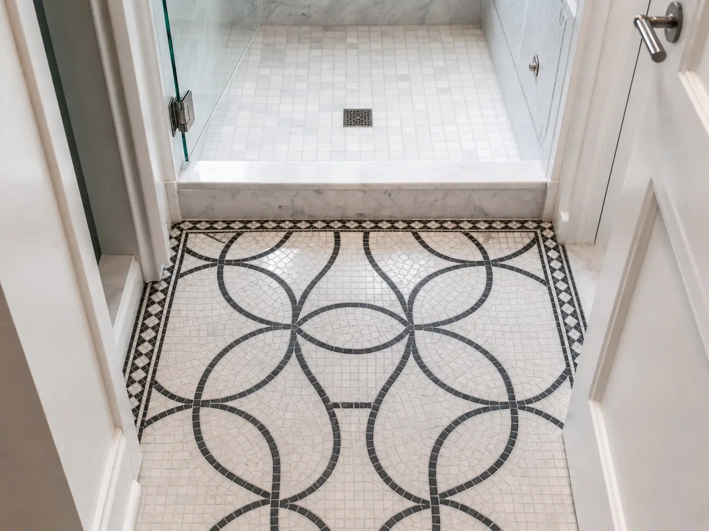 Bathroom floor in a custom interlocking-circle mosaic with a marble border, running into a glass shower enclosure