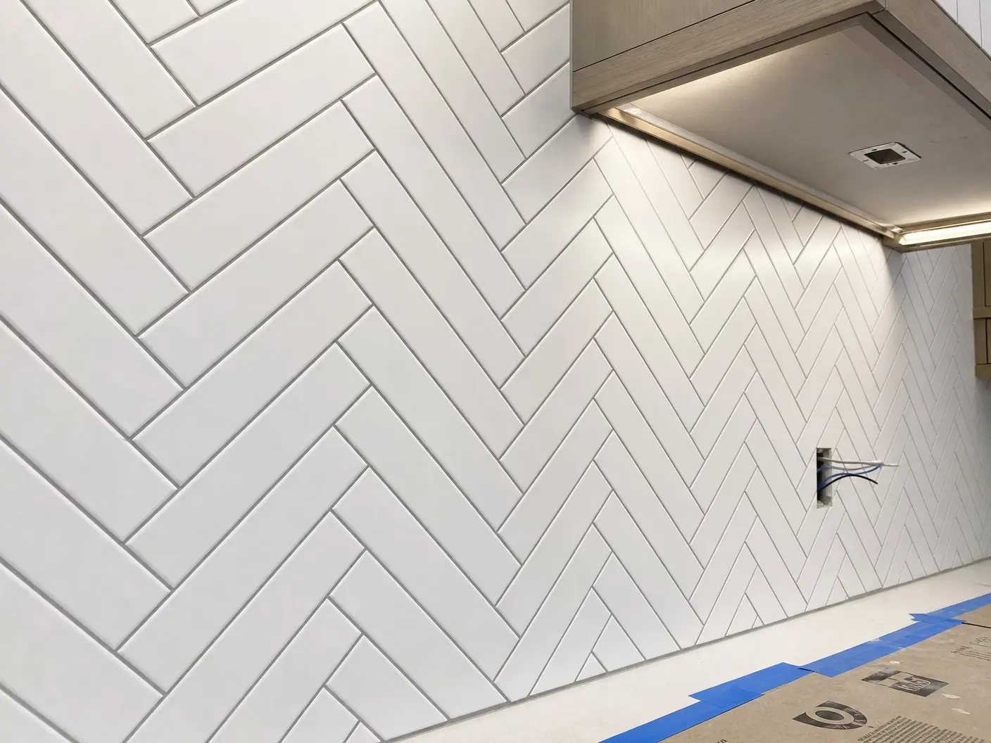 Kitchen backsplash in white herringbone subway tile running up to the underside of the cabinets