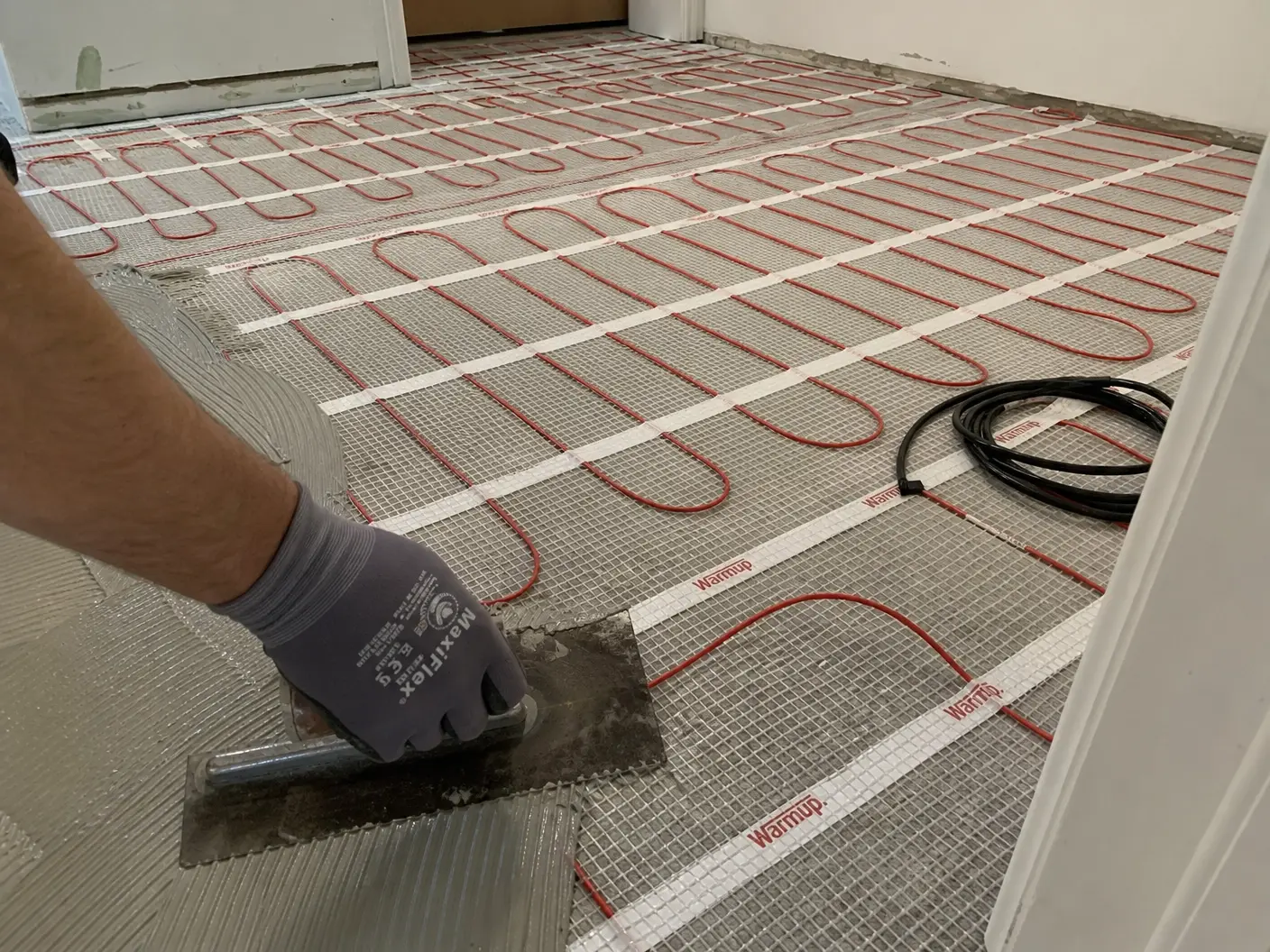 Heating mat rolled out and fixed across a prepared subfloor ready for tile