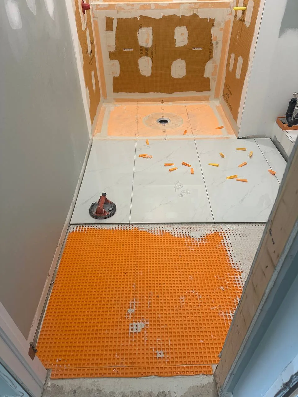 Curbless shower floor tiled level with the bathroom floor around a central drain