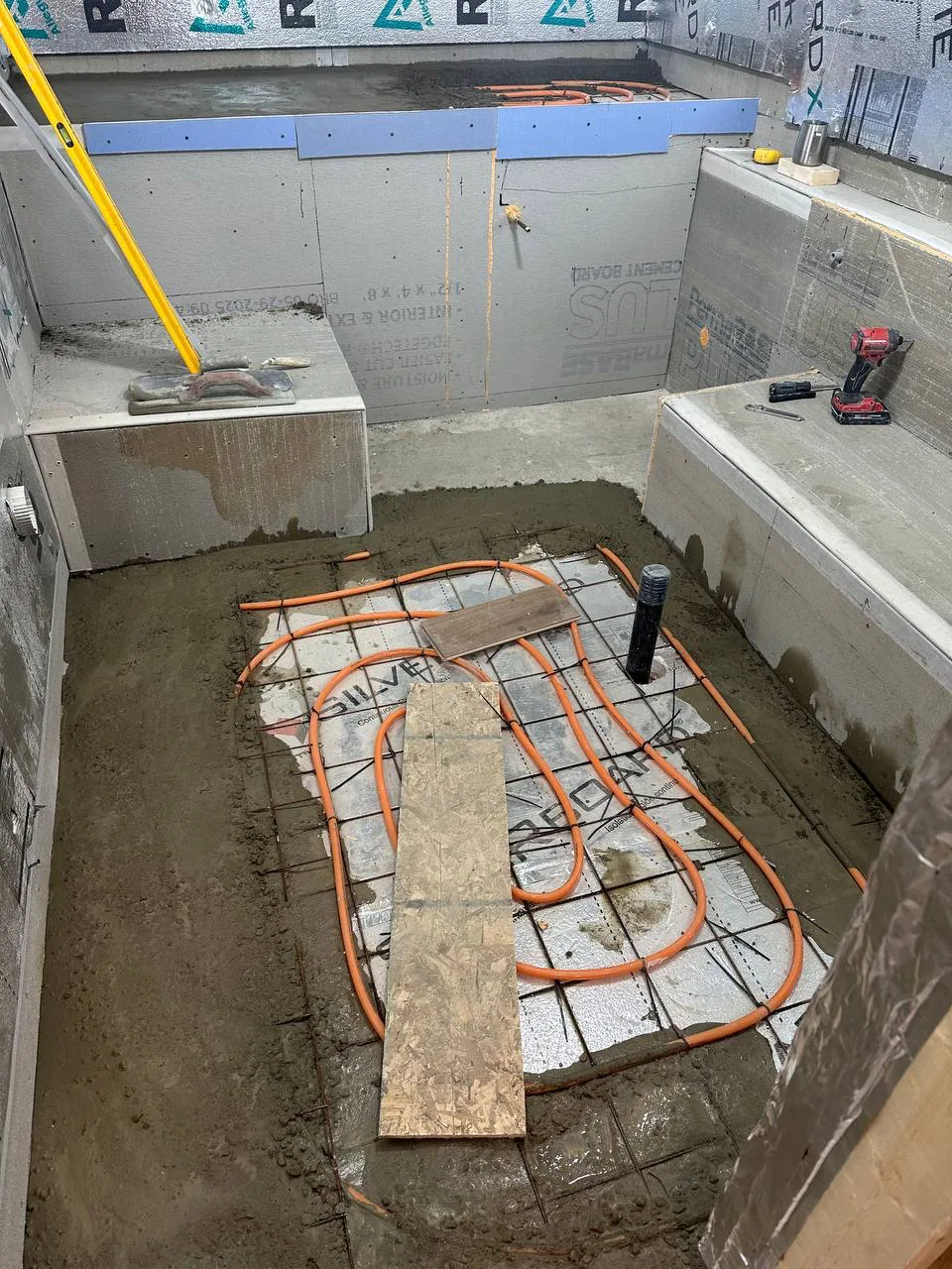 Wide view of the same basement with heating loops, benches formed and walls insulated, ready for concrete